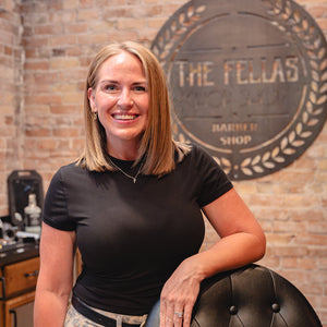 Woman behind a barber shop with a brick wall and 'The Fellast' sign.